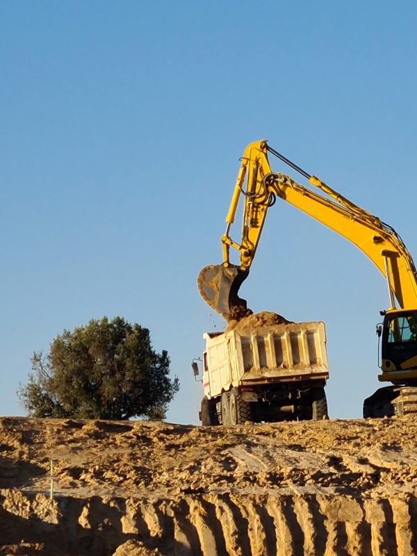 Excavator machine filling truck in construction site on sky background. Excavator working in Valdebebas, Madrid.